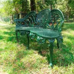 pair of green english garden benches with metal cane seats