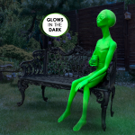 alien statue sitting on bench drinking can glow in dark
