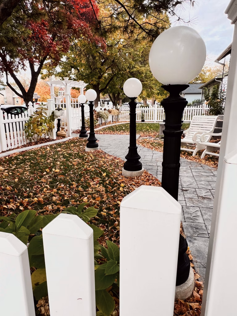 Customer Showcase Customer photo of white globe lamp posts from The Kings Bay lining a garden path behind a picket fence